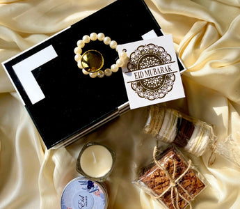 Eid Mubarak gift set with black box, pearl bracelet, cookies, macarons, candle, and card