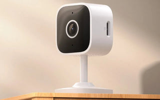 White smart security camera with wide lens on wooden surface for home monitoring
