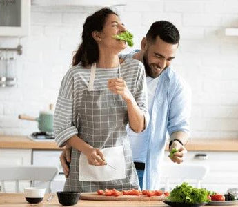 Happy couple cooking healthy food together in modern kitchen with fresh vegetables