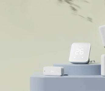 Smart home temperature and humidity sensor set with digital display and wireless modules on a modern surface.