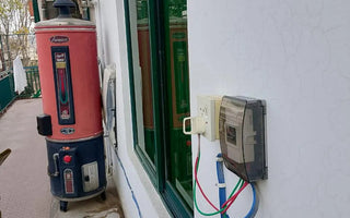 Outdoor electric geyser with smart WiFi switch and visible wiring installed on house wall
