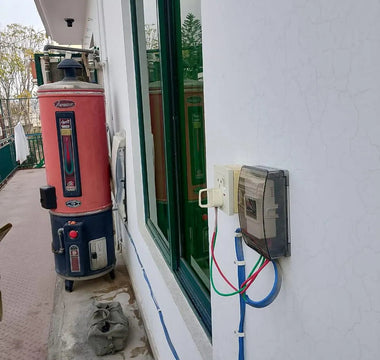 Outdoor smart electric geyser switch installation with visible wiring on house wall