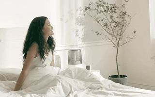 Woman relaxing in smart bedroom with humidifier and plant, enjoying modern home comfort