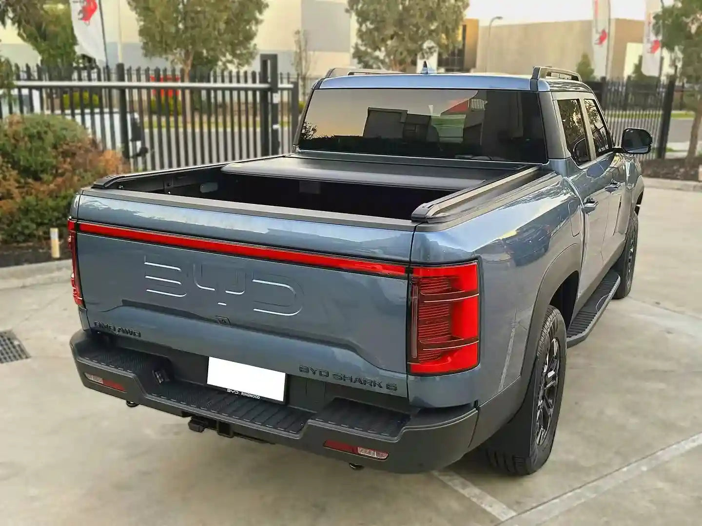 BYD Shark 6 pickup truck rear view with tailgate and LED lights, parked outdoors
