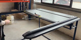 Person testing durable black metal table in warehouse with tools and storage shelves